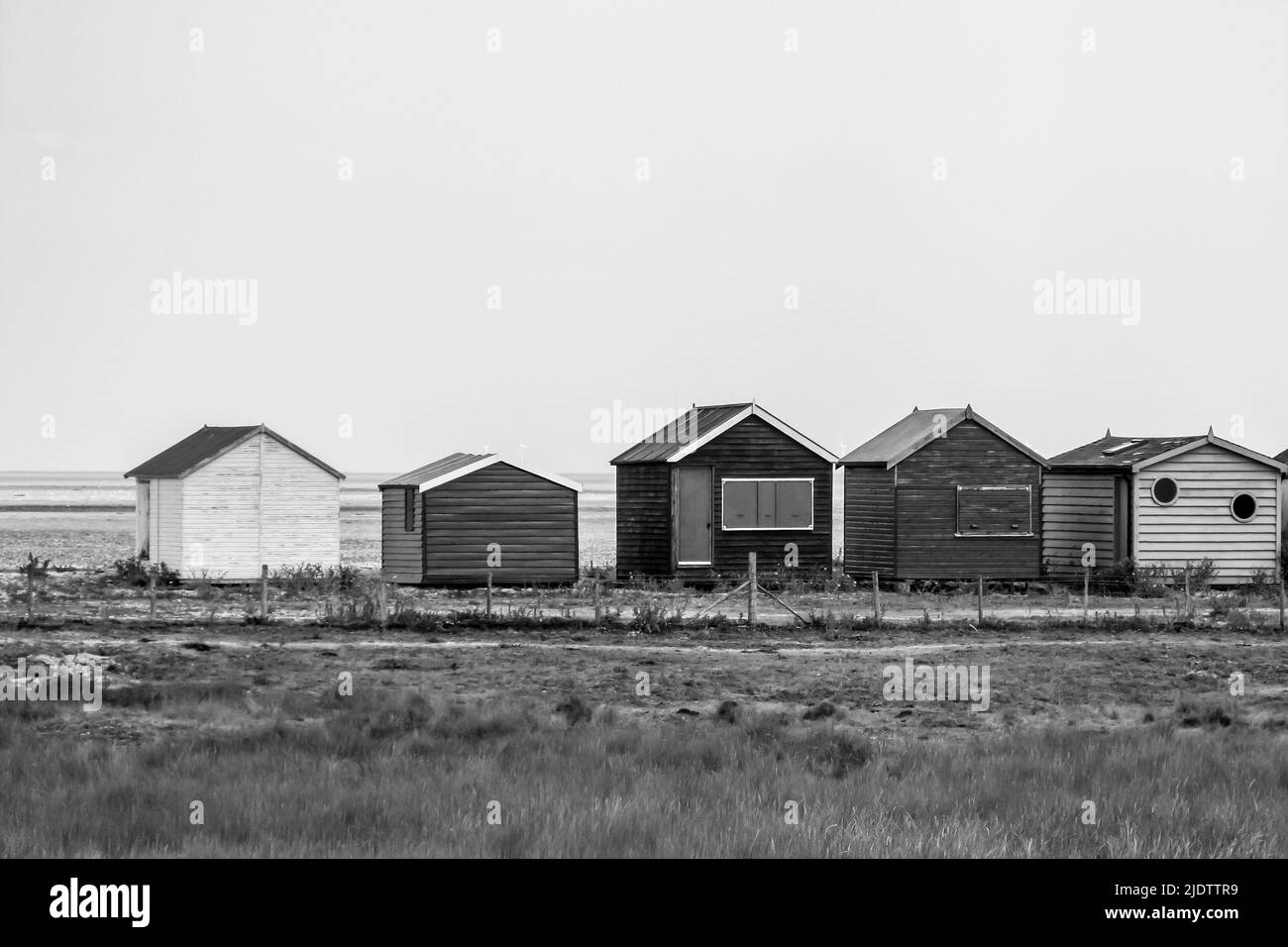 Petites cabanes de plage en bois en noir et blanc à Seasalter Beach, juste à l'extérieur de Whitstable, Kent, Royaume-Uni Banque D'Images