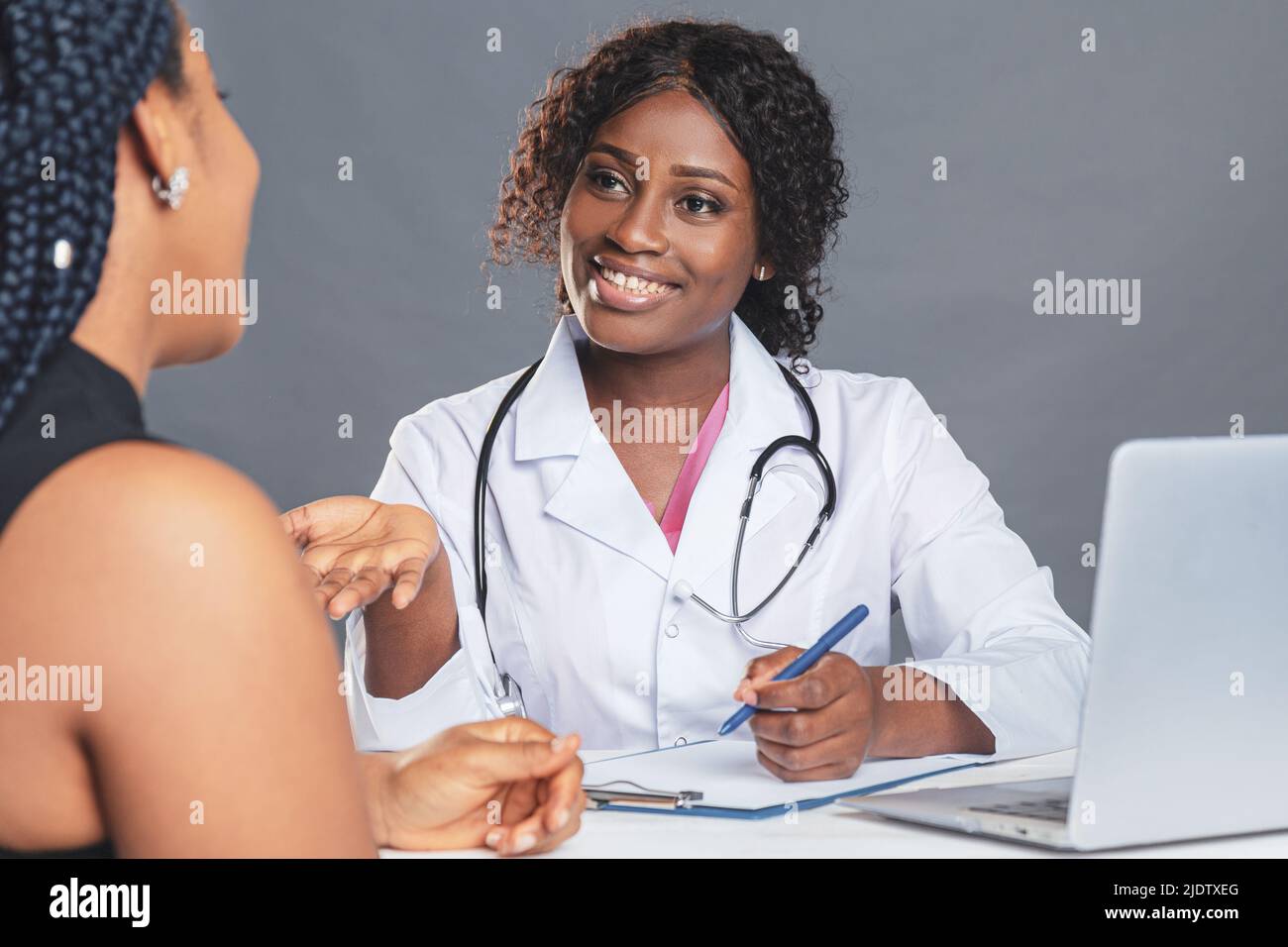 Femme afro-américaine médecin en cabinet médical avec un patient tout en portant un masque de protection pendant un rendez-vous médical Banque D'Images