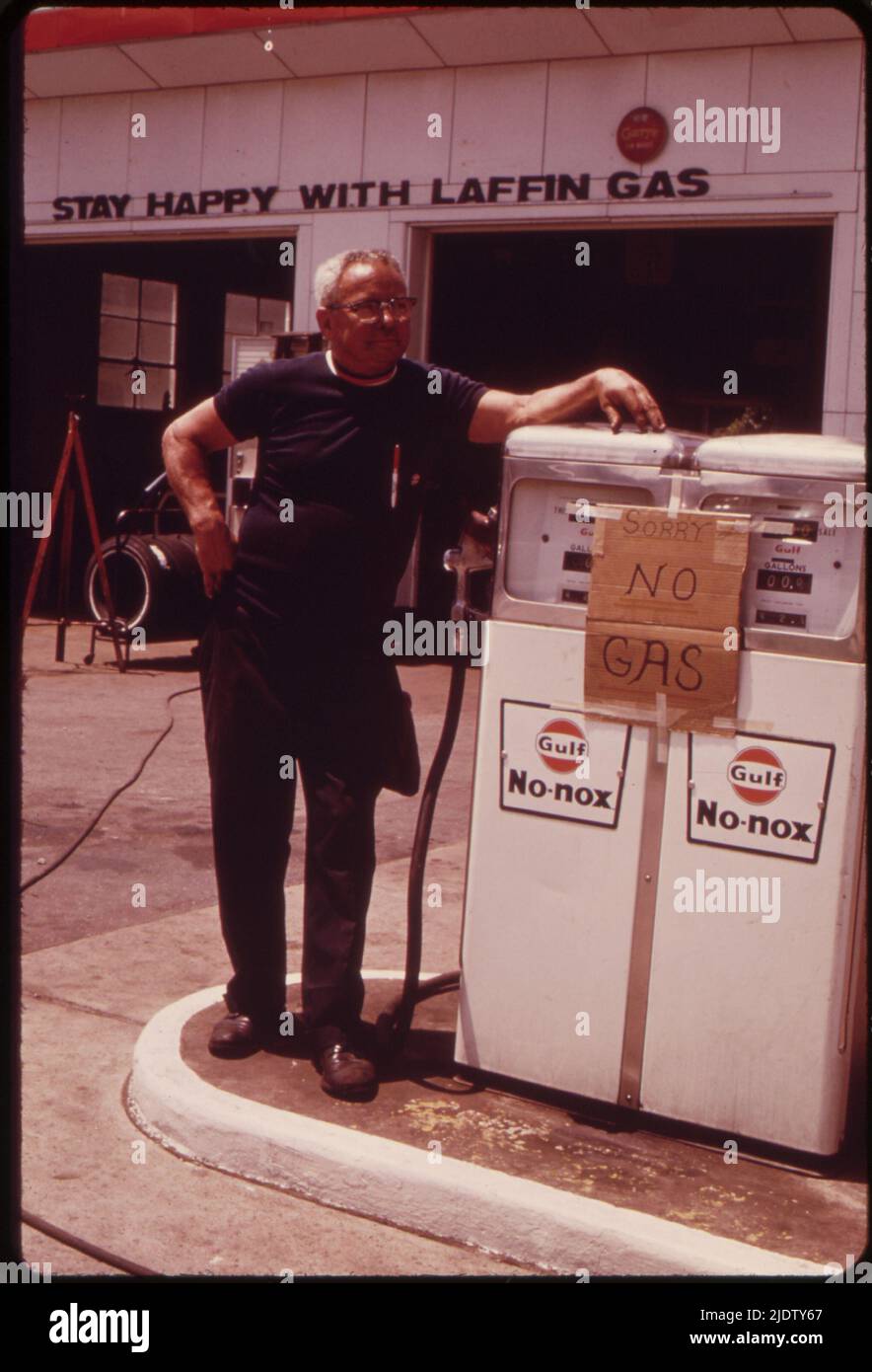 L'opérateur de la station-service se tient près d'une pompe à gaz vide pendant la hauteur de la pénurie de gaz, pas d'emplacement, 1973. Banque D'Images