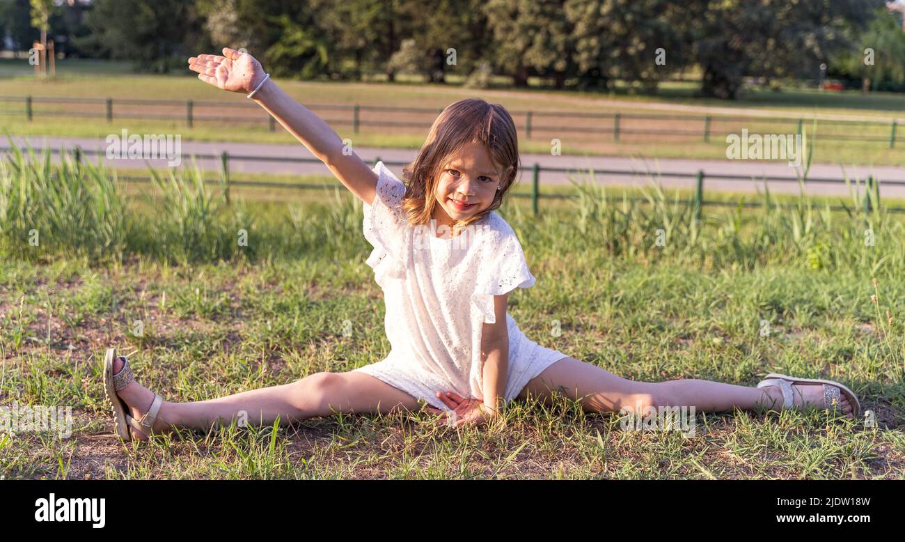 mignon petite fille fait des exercices de gymnastique artistique dans le parc Banque D'Images