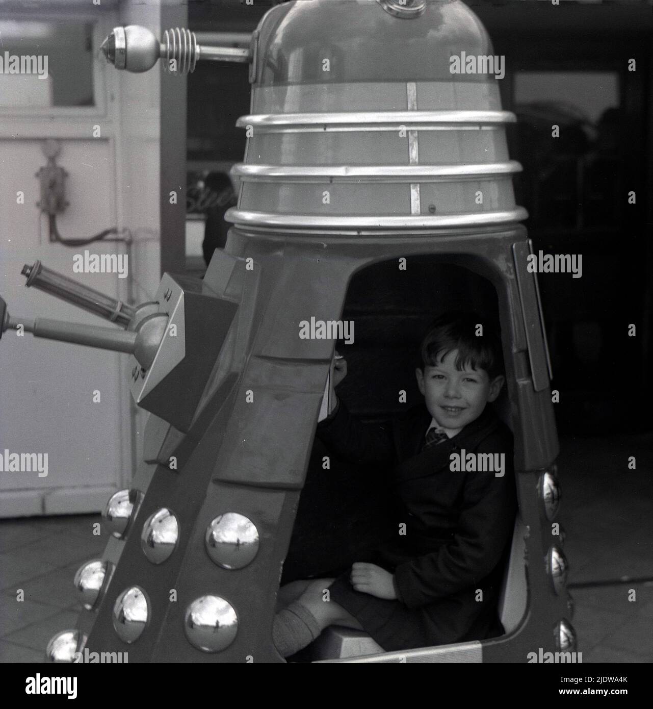 1967, historique, un jeune garçon assis dans un Dalek, Angleterre, Royaume-Uni. Une race extraterrestre fictive de mutants ou de robots, les Daleks sont apparus pour la première fois dans le programme de télévision de science-fiction Briitsh Doctor Who en 1963. Créé par Terry Nation, les Daleks sont rapidement devenus le personnage le plus populaire du BBC. Les extraterrestres ont été conçus par Raymond Cusick, qui, en tant qu'employé salarié de la BBC à l'époque, n'a reçu aucun des revenus générés par les marchandises Daleks, contrairement à Nation qui l'a fait, tout comme un auteur de script indépendant. Banque D'Images