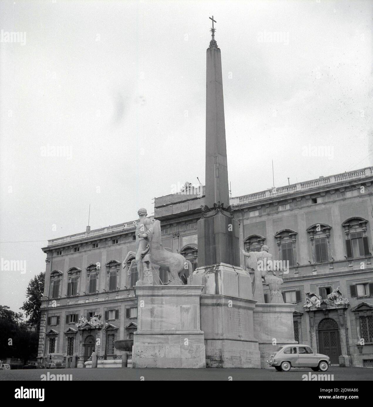 1950s, historique, grande colonne de pierre avec religieux, croix chrétienne sur le dessus avec des statures de centurions et des chevaux à la base, Naples, Italie. Voiture Fiat 500 garée à côté. Banque D'Images