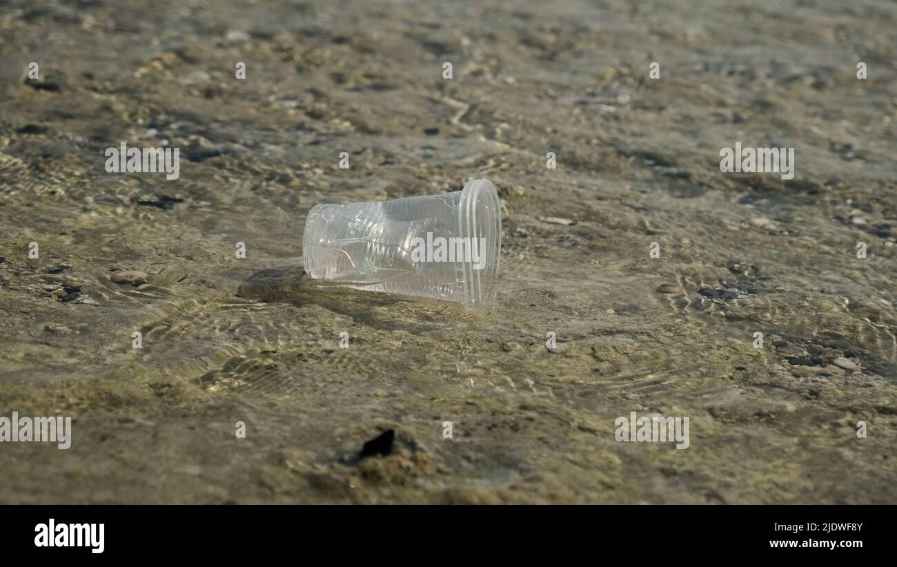 La tasse en plastique transparent est transportée par le vent jusqu'à la mer dans la zone côtière. Pollution plastique de la zone de surf. Mer rouge, Égypte Banque D'Images
