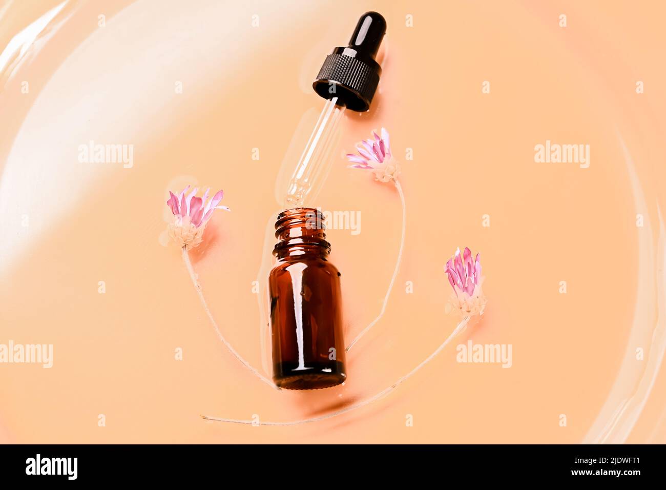 Laboratoire cosmétique abstrait. Flacons en verre ambré foncé sur fond liquide beige. Cosmétiques naturels pour les soins, homéopathie. Style plat, vue de dessus Banque D'Images