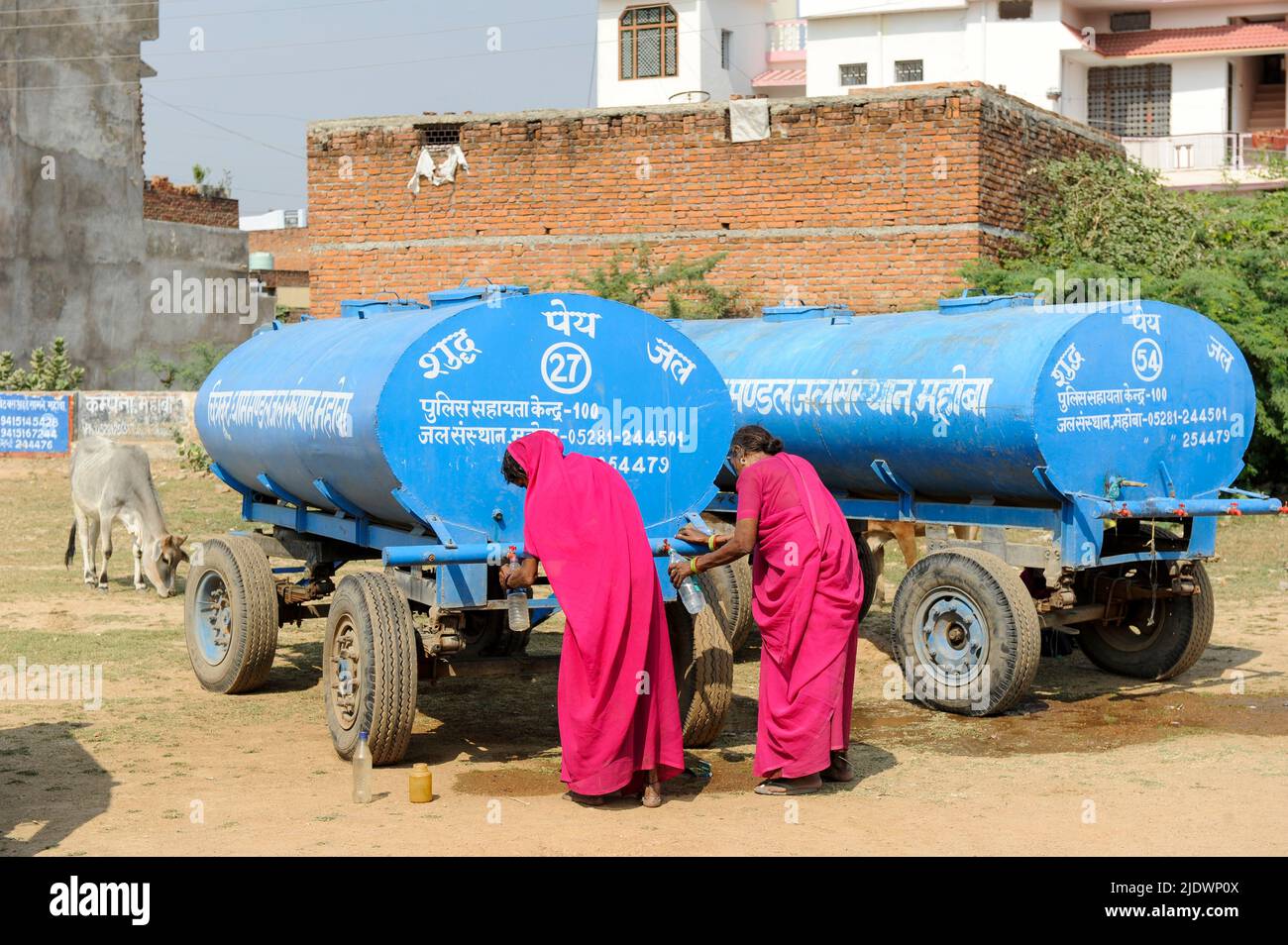 INDE, Uttar Pradesh, Bundelkhand, Mahoba, pénurie d'eau, Femmes en saree rose au réservoir d'eau bleu remplissant la bouteille en plastique avec de l'eau potable, lors d'un rassemblement de femmes mouvement Gulabi Gang Banque D'Images