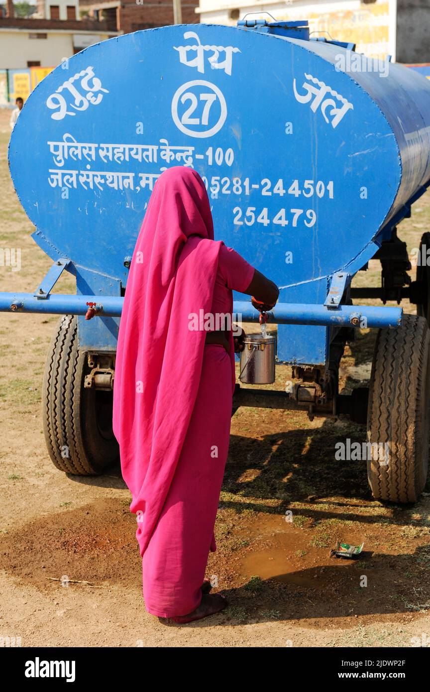 INDE, Uttar Pradesh, Bundelkhand, Mahoba, pénurie d'eau, Femmes en saree rose au réservoir d'eau bleu remplissant la bouteille d'eau potable, lors d'un rassemblement de Gulabi Gang Banque D'Images