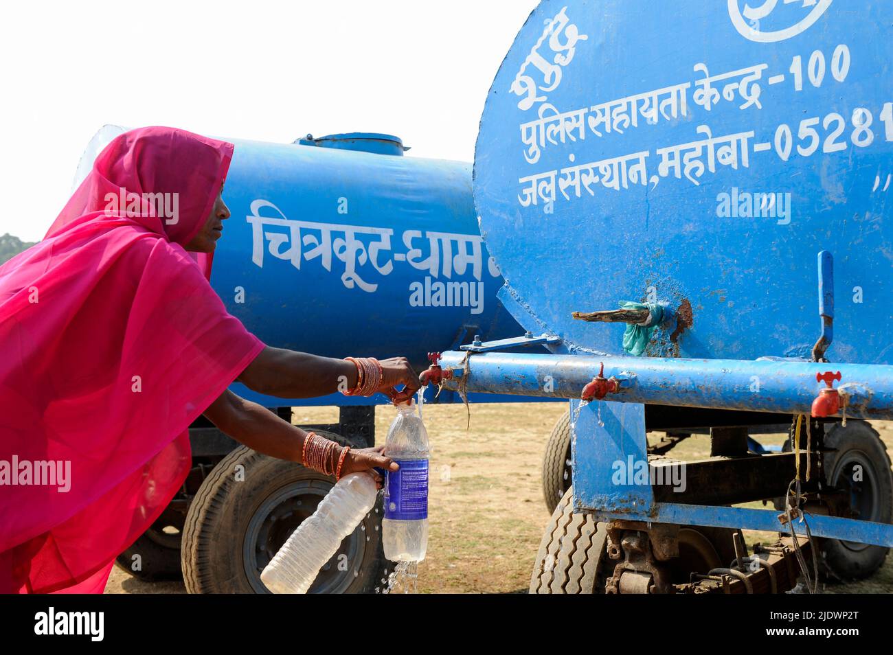 INDE, Uttar Pradesh, Bundelkhand, Mahoba, pénurie d'eau, Femmes en saree rose au réservoir d'eau bleu remplissant la bouteille en plastique avec de l'eau potable, lors d'un rassemblement de femmes mouvement Gulabi Gang Banque D'Images