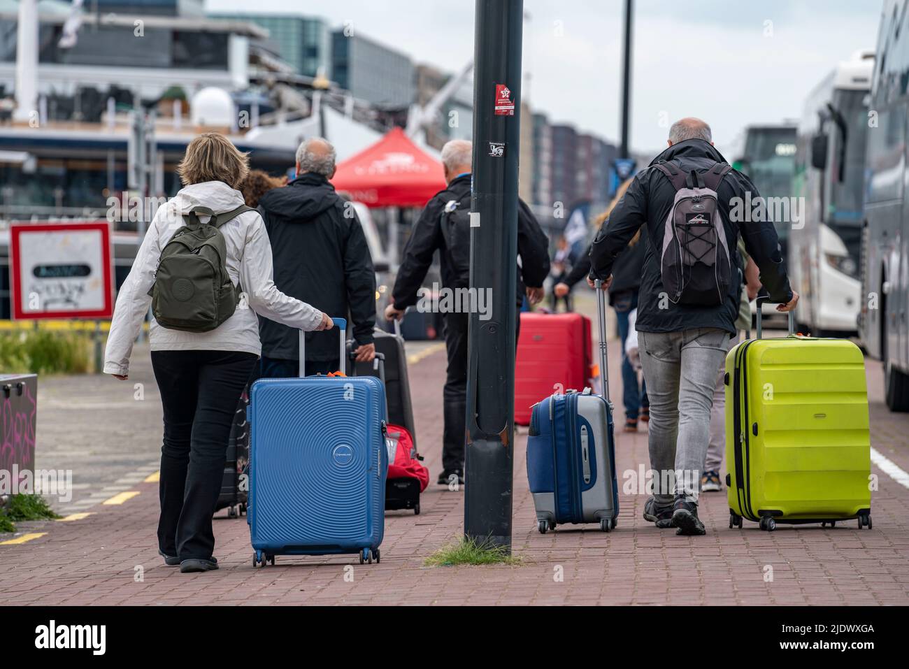 Voyageurs en route vers un bateau de croisière fluvial au quai de l'IJ, transportant leurs bagages, valises à roulettes, de la gare centrale au navire, AMS Banque D'Images