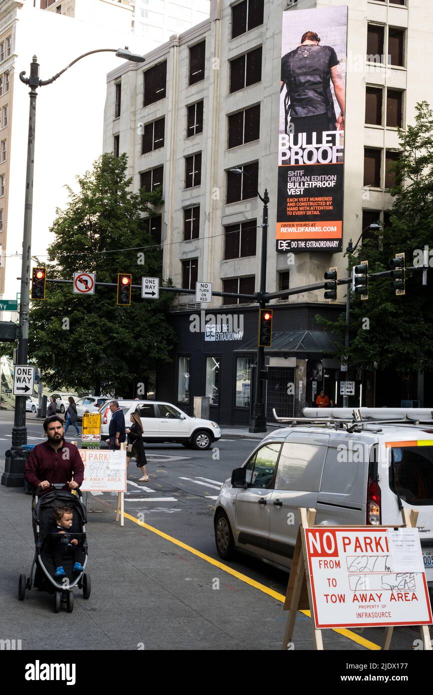 Seattle, États-Unis. 23rd juin 2022. Westlake quartier commerçant, un homme passant avec un enfant comme un panneau d'affichage électronique affiche une annonce pour Bullet Proof Vêtes. La police de Seattle et les responsables de la ville luttent pour lutter contre le crime en cours dans le centre-ville. Une augmentation des sans-abri causée par la pandémie et l'augmentation des loyers a entraîné une augmentation de la criminalité et de la consommation de drogues dans la ville. James Anderson/Alay Live News Banque D'Images