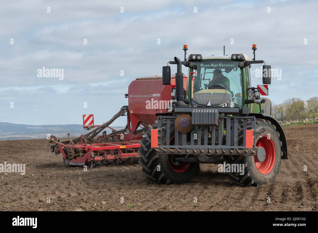 Un tracteur Fendt tractant un semoir Horsch manœuvrant des rangées au bord d'un champ labouré Banque D'Images