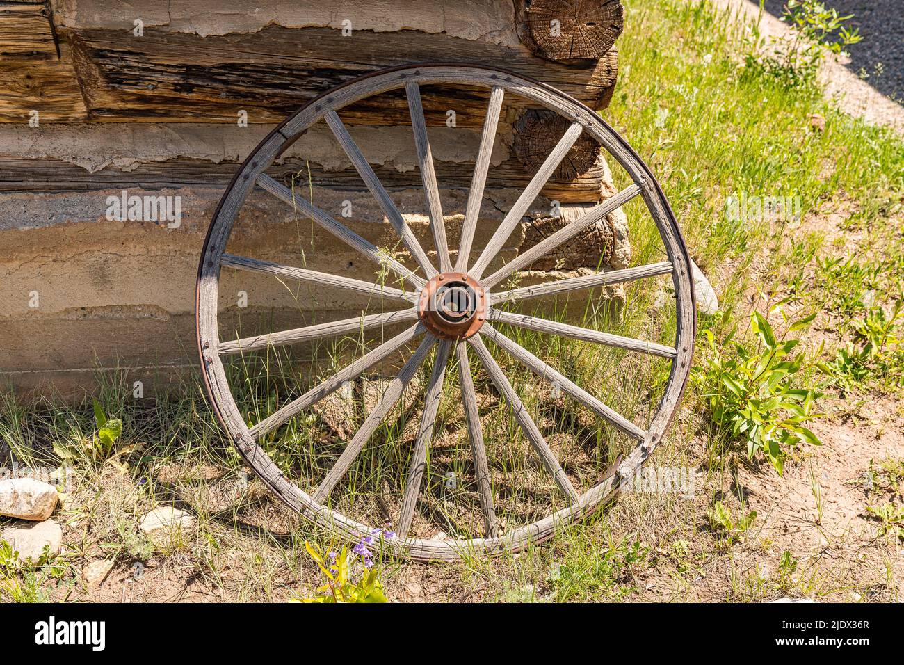 Ancienne roue de wagon abîmé penchée contre un mur de la cabine en rondins Banque D'Images