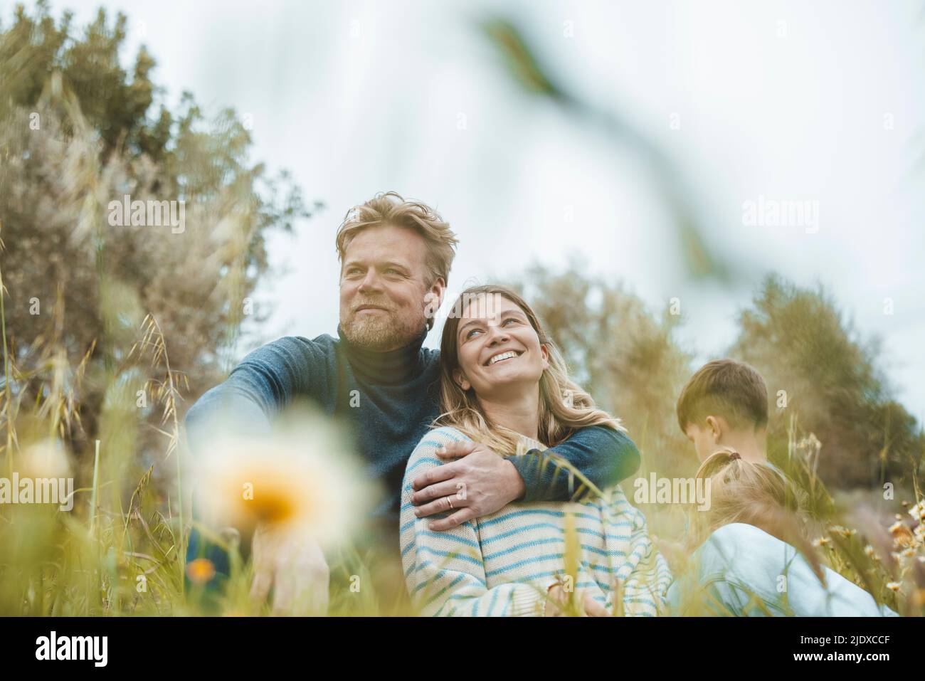 Homme souriant avec le bras autour de la femme assis dans la prairie Banque D'Images
