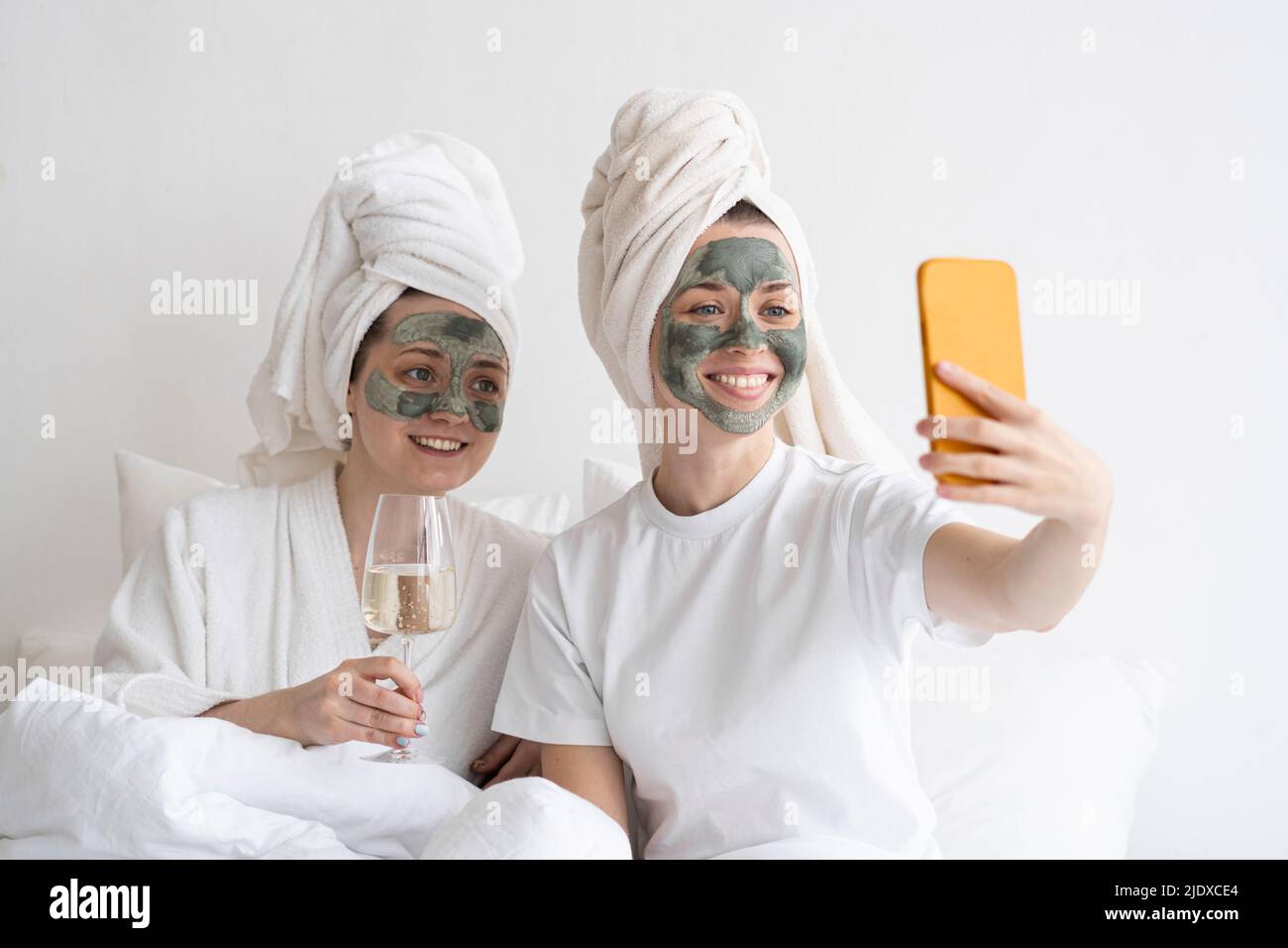 Des amis heureux portant des masques faciaux emportant un selfie sur un téléphone portable Banque D'Images