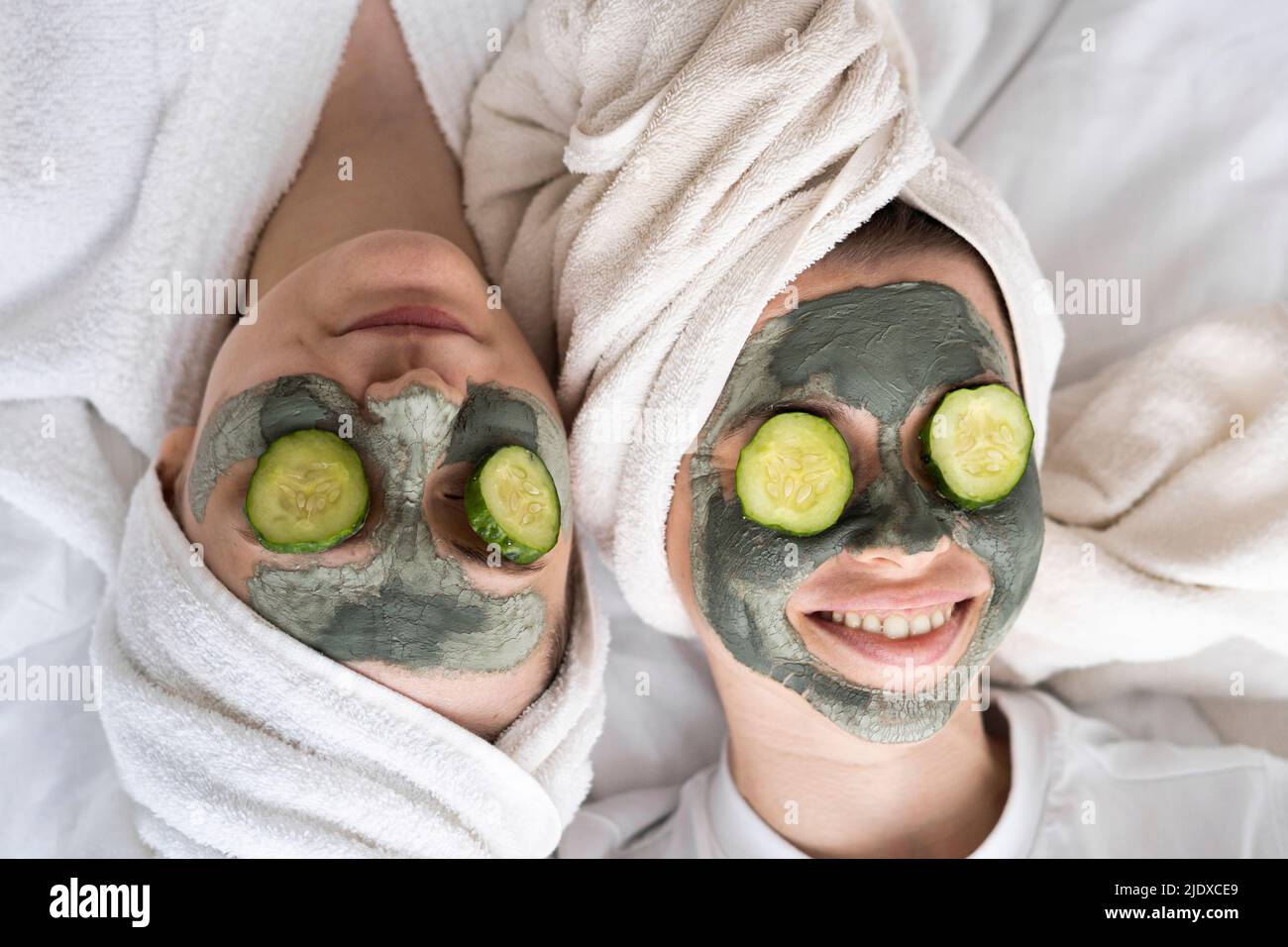 Des amis heureux portant des masques faciaux se détendent au lit à la maison Banque D'Images
