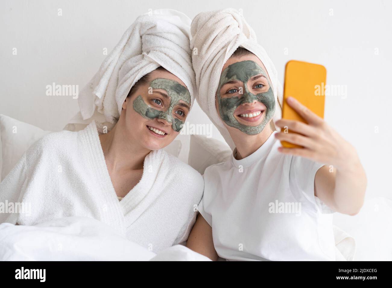 Des amis heureux portant un masque facial emportant un selfie sur un smartphone Banque D'Images