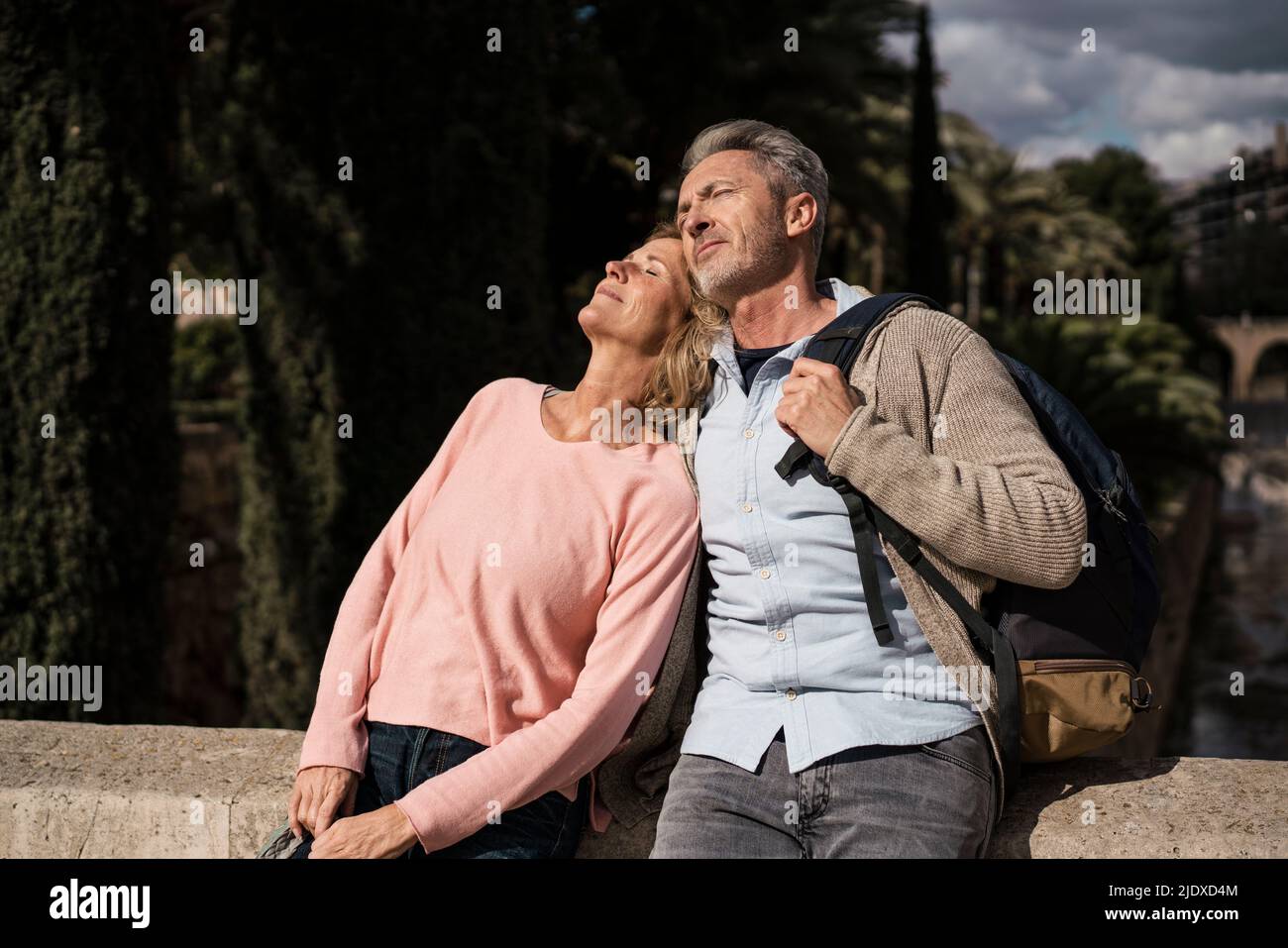 Touristes matures avec les yeux fermés profitant de la lumière du soleil Banque D'Images