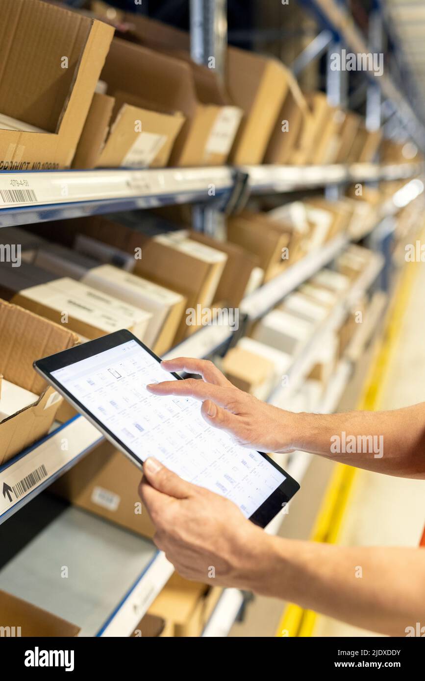 Les mains du personnel analysent la liste des tablettes PC par rack dans l'entrepôt Banque D'Images