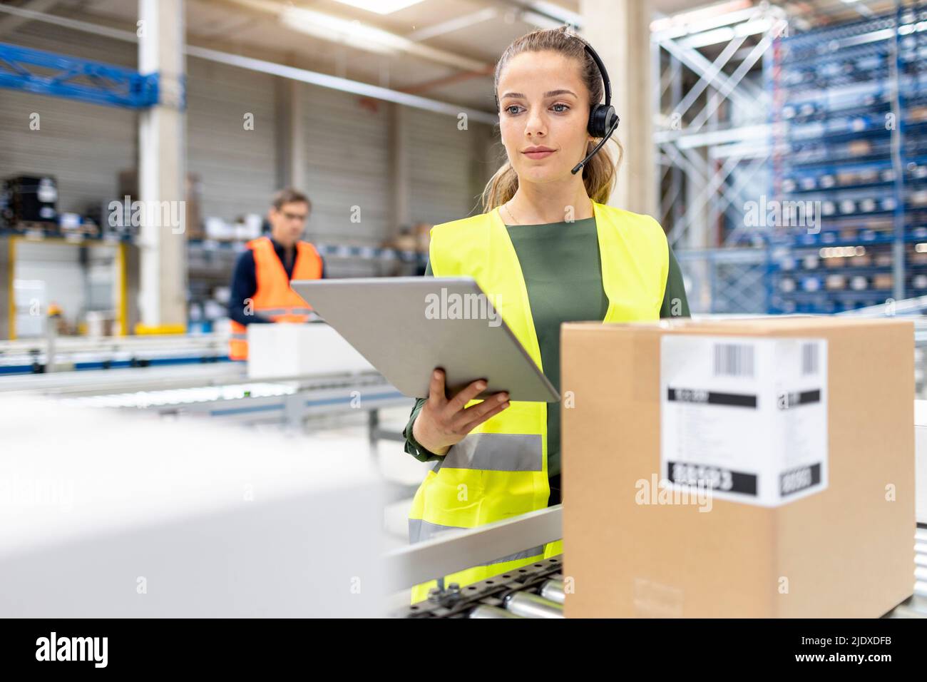 Jeune travailleur avec un PC tablette examinant des boîtes en carton dans l'entrepôt Banque D'Images