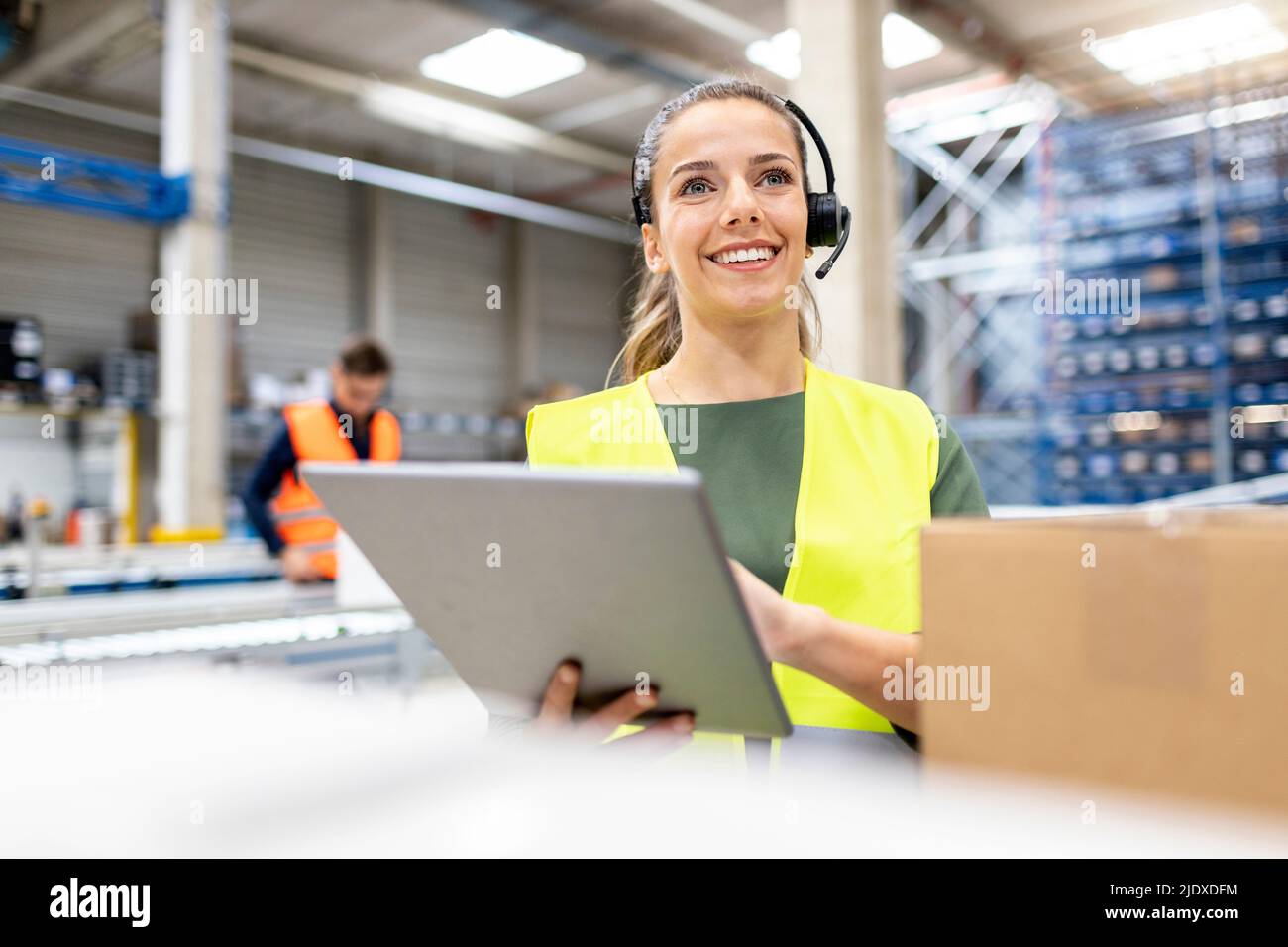 Jeune travailleur heureux debout avec un PC tablette travaillant dans l'entrepôt Banque D'Images