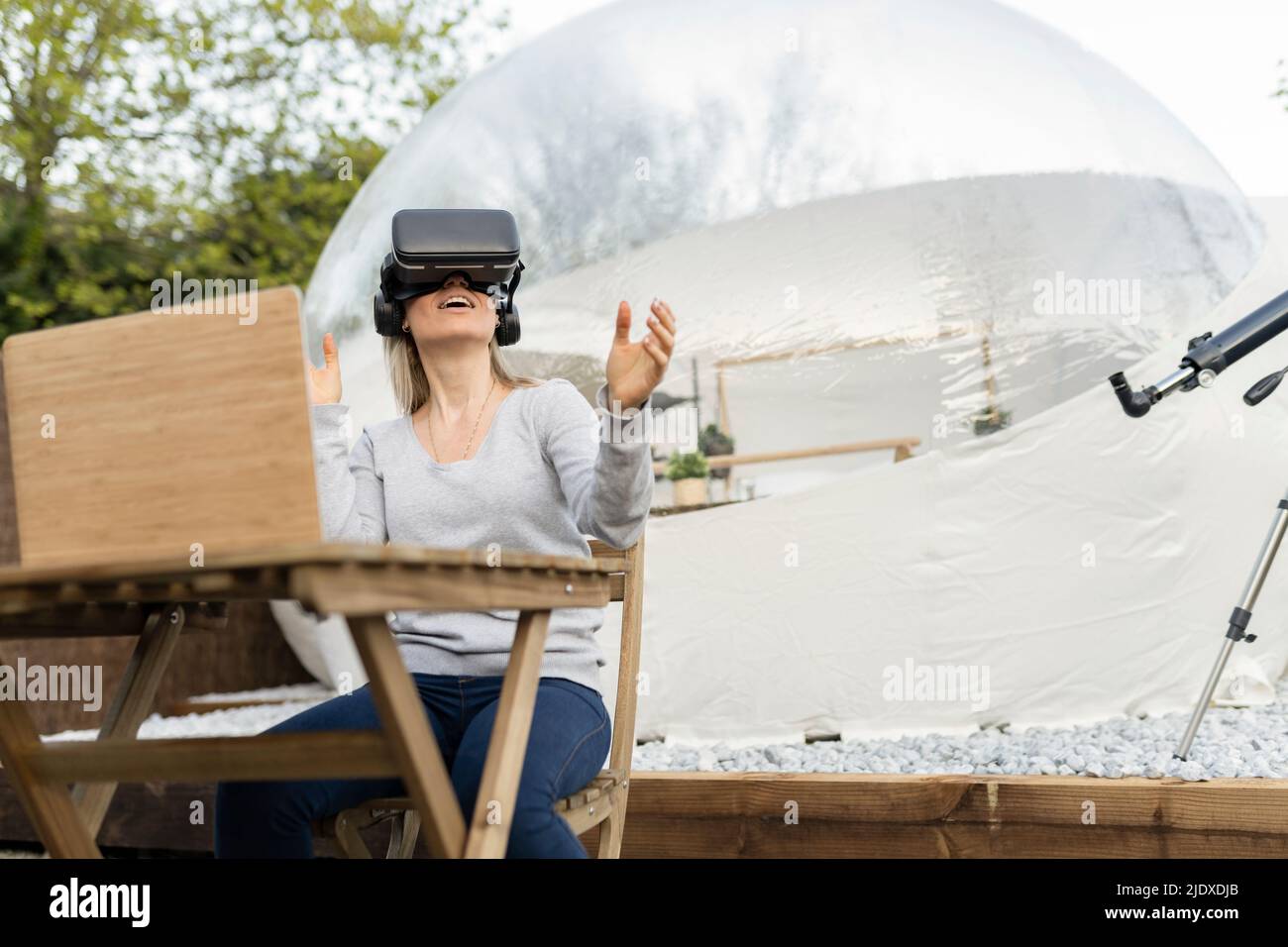 Femme portant un simulateur de réalité virtuelle assis avec un ordinateur portable Banque D'Images