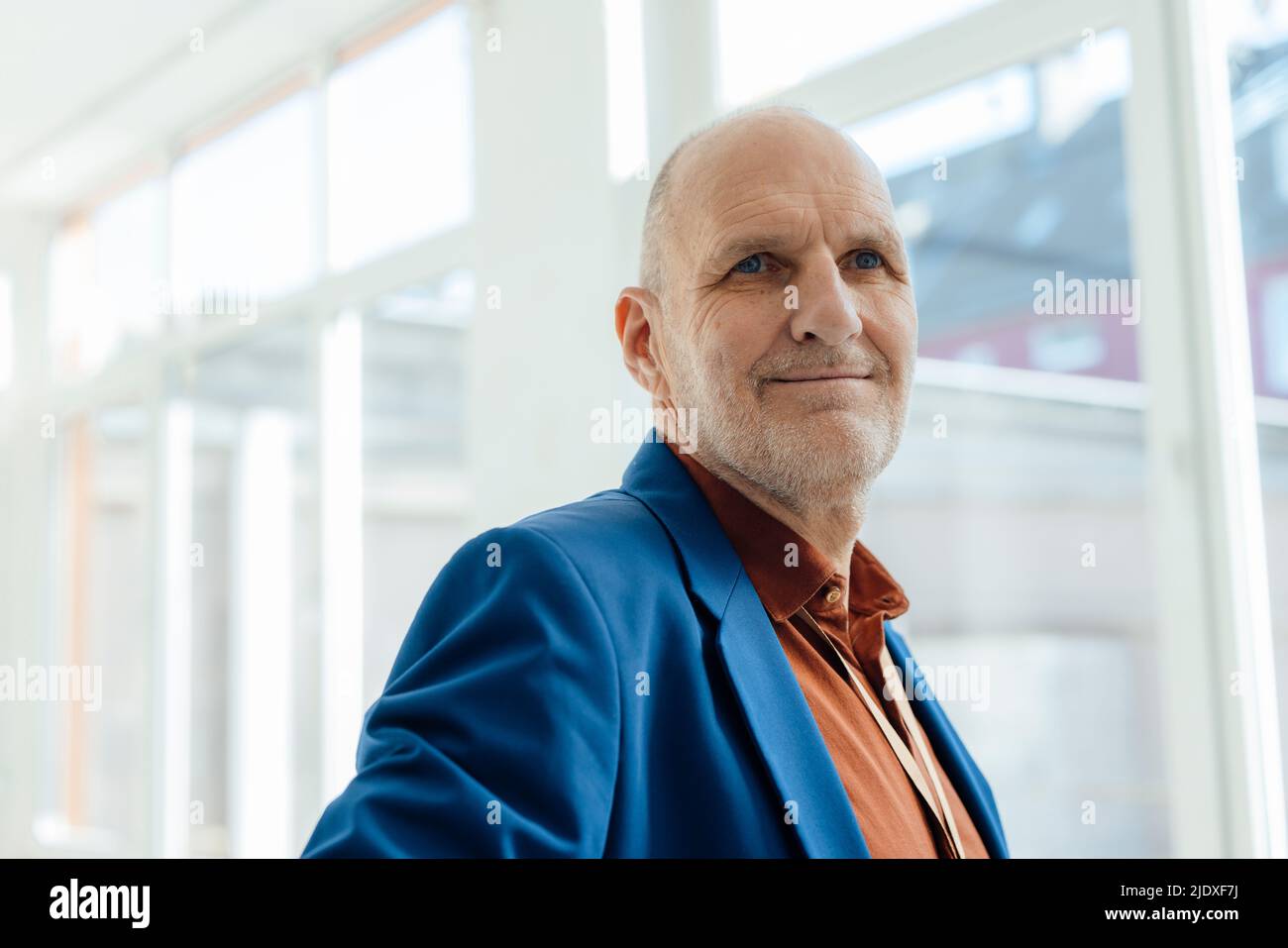 Homme d'affaires souriant portant un blazer bleu au bureau Banque D'Images