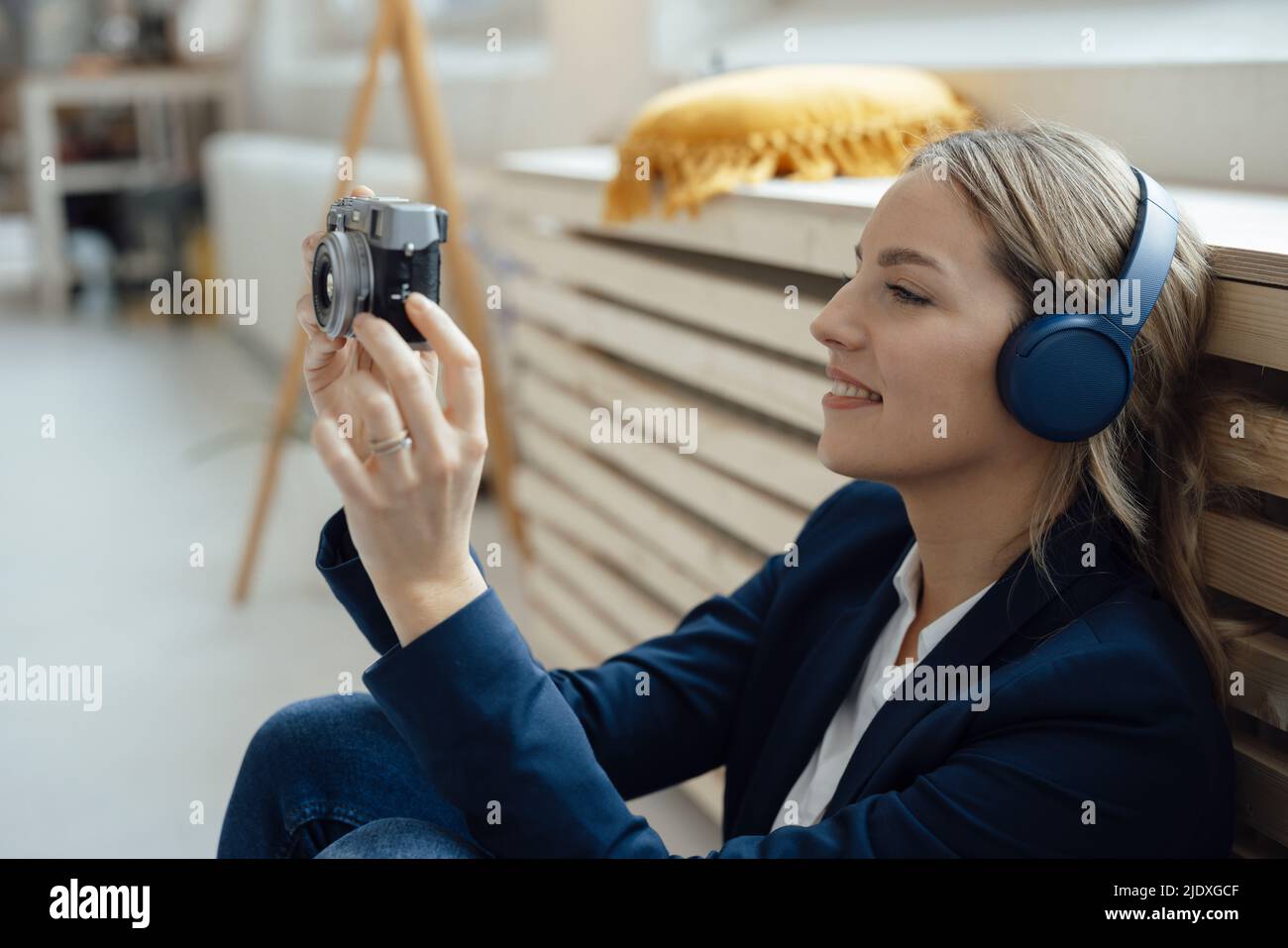 Femme d'affaires souriante photographiant à travers un appareil photo avec un casque Banque D'Images