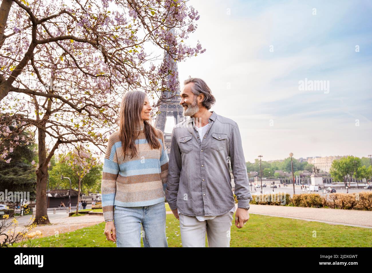 Couple mûr souriant regardant les uns les autres marcher en face de la tour Eiffel, Paris, France Banque D'Images