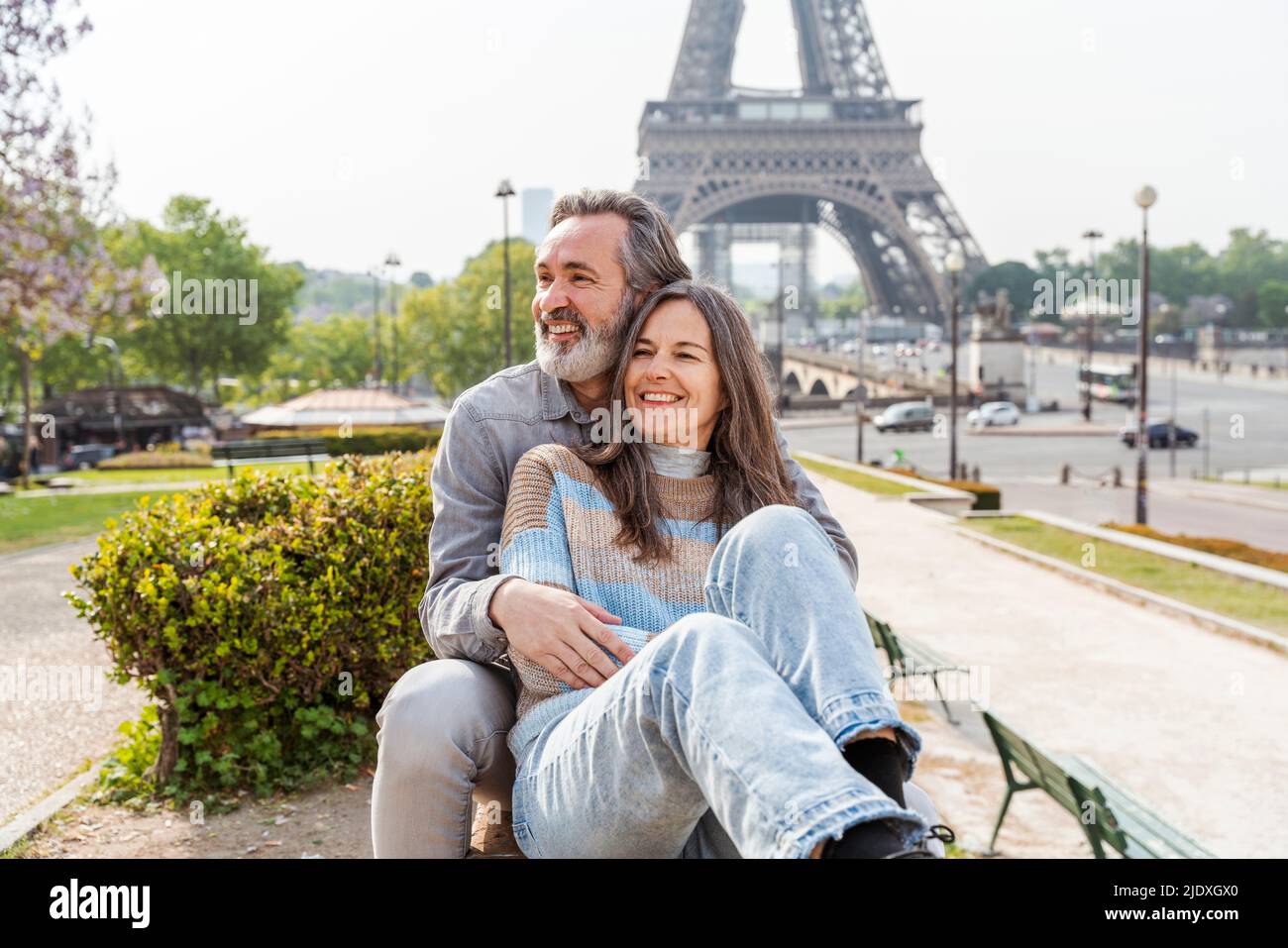 Joyeux homme et femme mûrs assis ensemble au parc en face de la tour Eiffel, Paris, France Banque D'Images