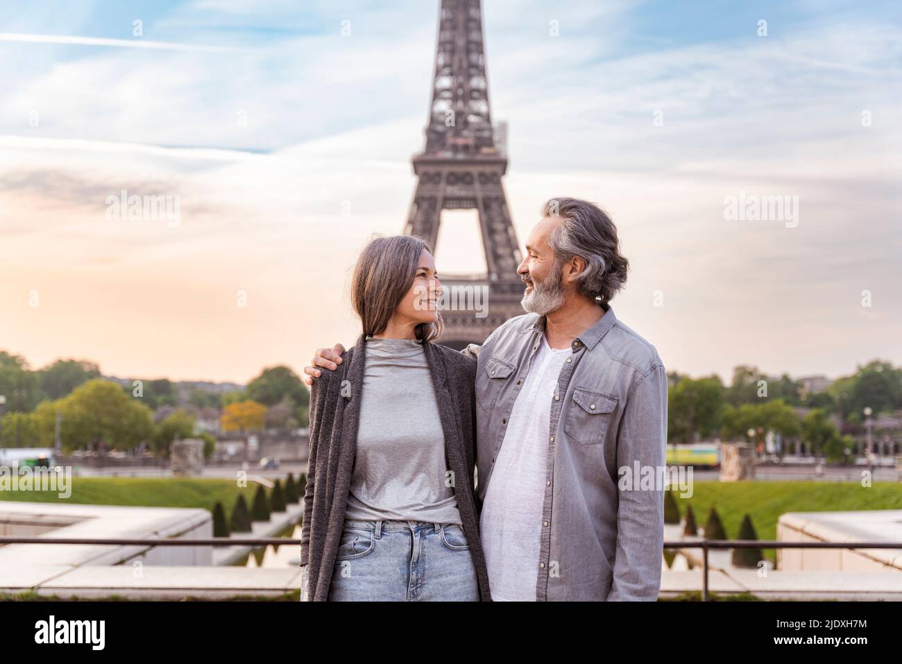 Homme souriant avec le bras autour de la femme debout devant la Tour Eiffel, Paris, France Banque D'Images