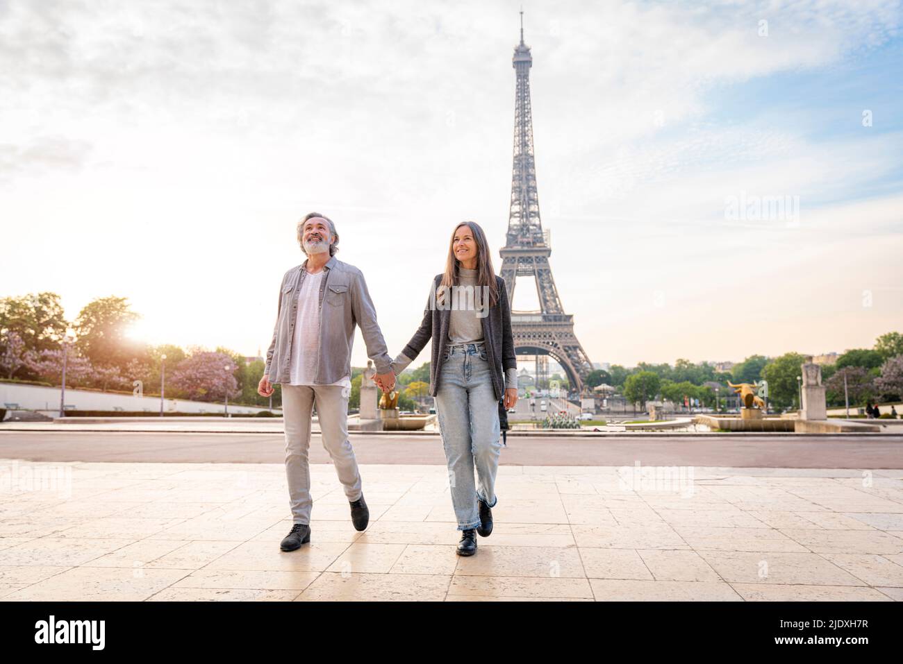 Heureux couple d'âge mûr tenant les mains et marchant devant la Tour Eiffel, Paris, France Banque D'Images