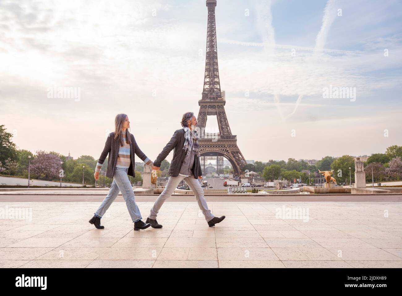 Couple d'âge mûr tenant les mains et marchant devant la Tour Eiffel, Paris, France Banque D'Images