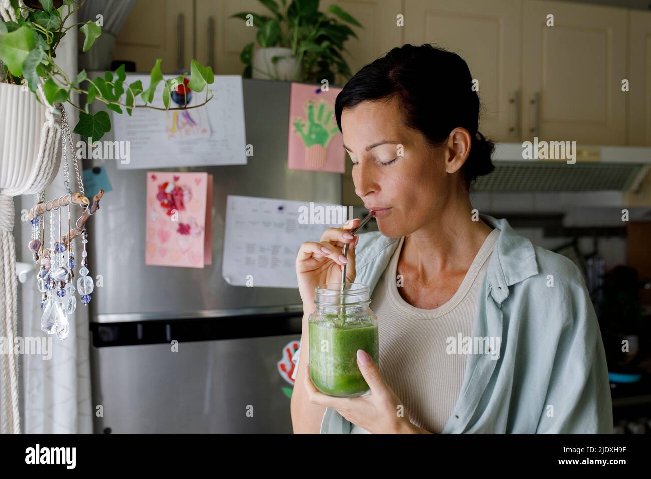 Femme buvant du smoothie sain de la paille à la maison Banque D'Images