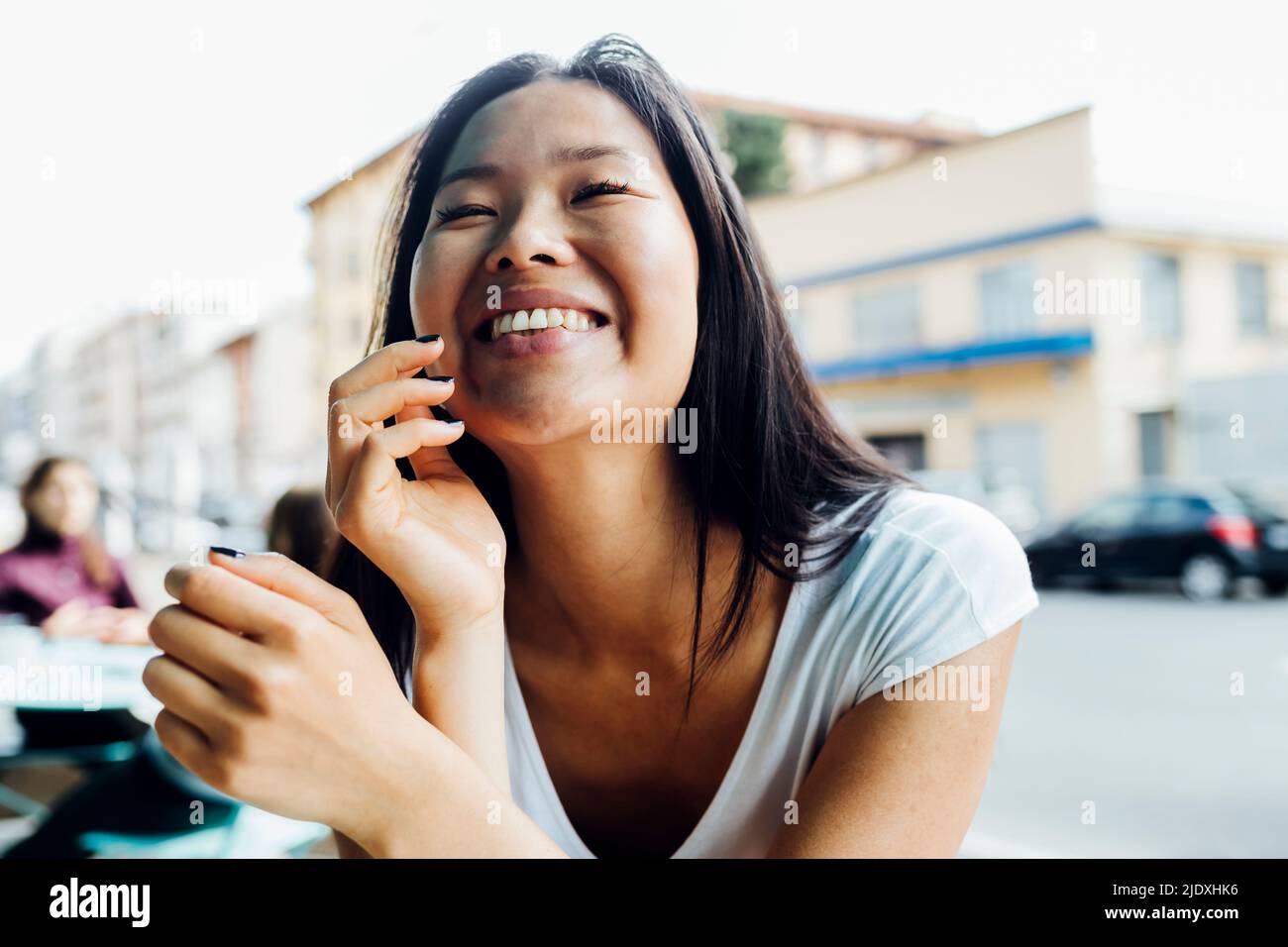 Jeune femme gaie avec les yeux fermés assis au café-terrasse Banque D'Images