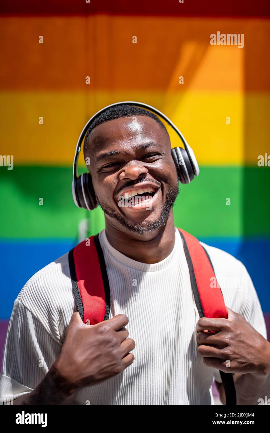 Un jeune homme heureux qui écoute de la musique avec un casque sans fil par beau temps Banque D'Images