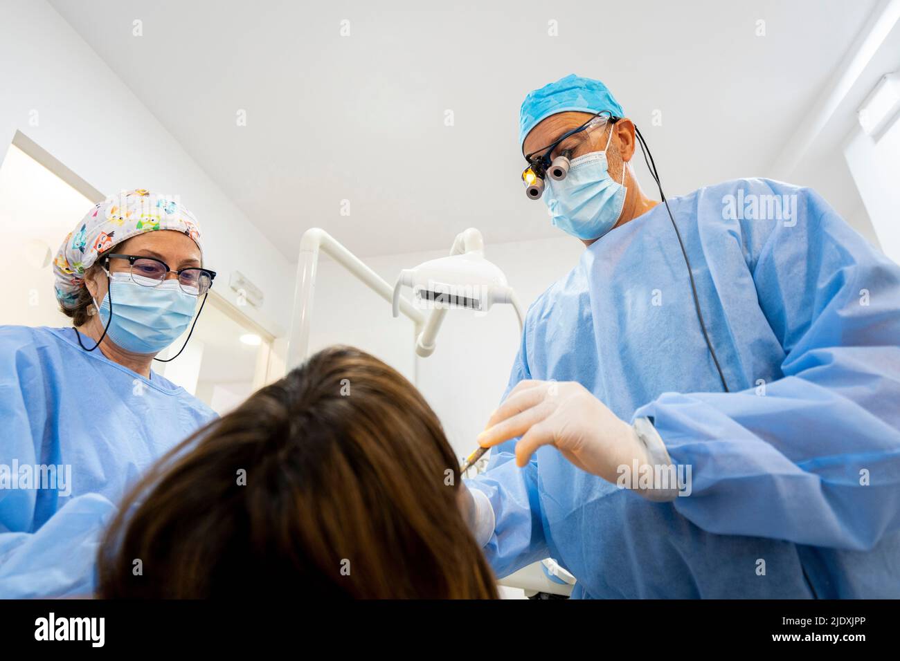 Dentiste avec infirmière traitant la femme à la clinique Banque D'Images