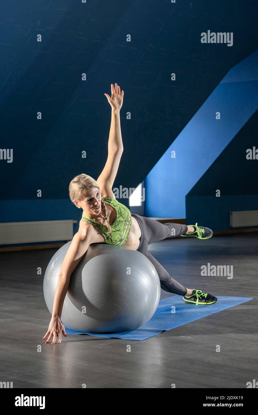 Femme faisant de l'exercice d'étirement avec le ballon de fitness au club de santé Banque D'Images