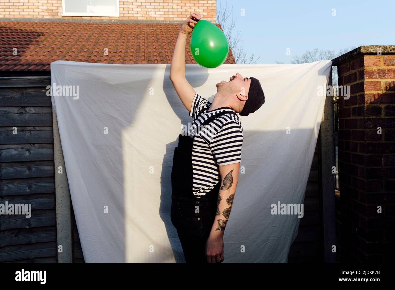 Homme avec la bouche ouverte tenant le ballon vert à l'arrière cour Banque D'Images
