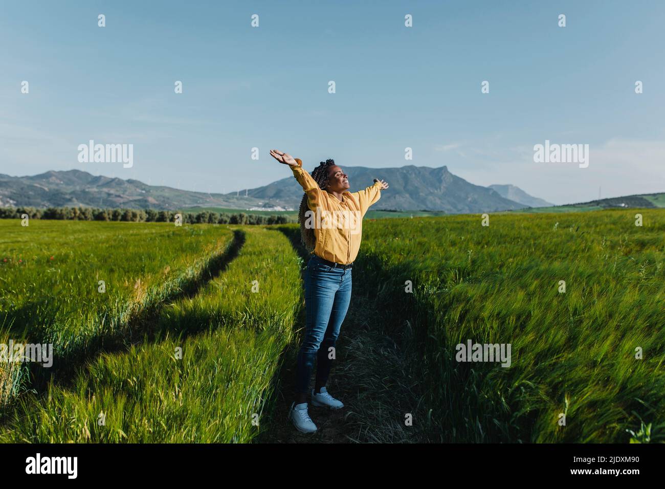Femme souriante debout avec les bras étirés dans la prairie Banque D'Images