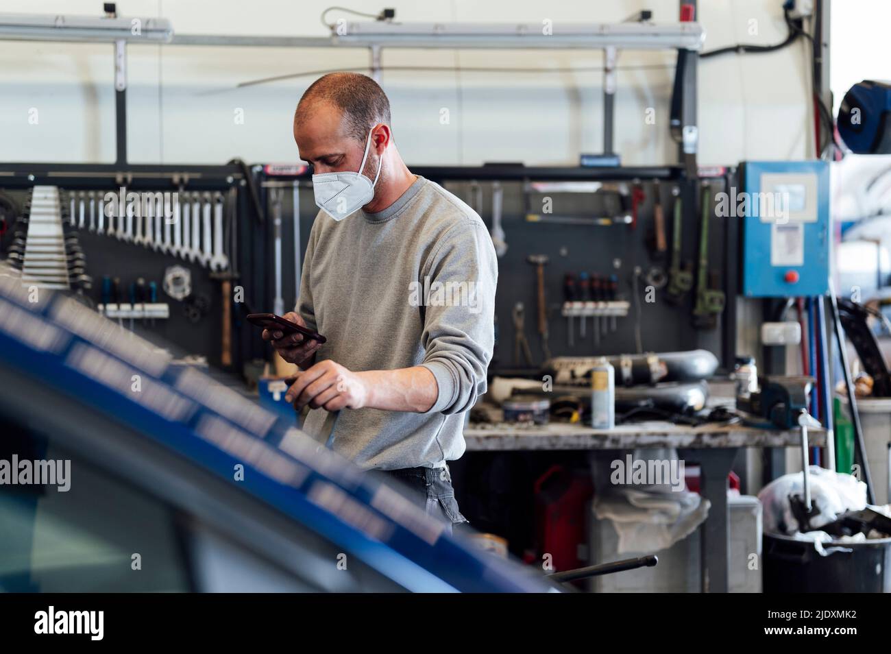 Mécanicien utilisant un téléphone portable dans un atelier automobile Banque D'Images