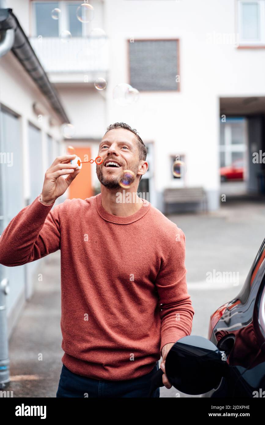 Un homme heureux qui soufflait des bulles à l'extérieur du bâtiment Banque D'Images