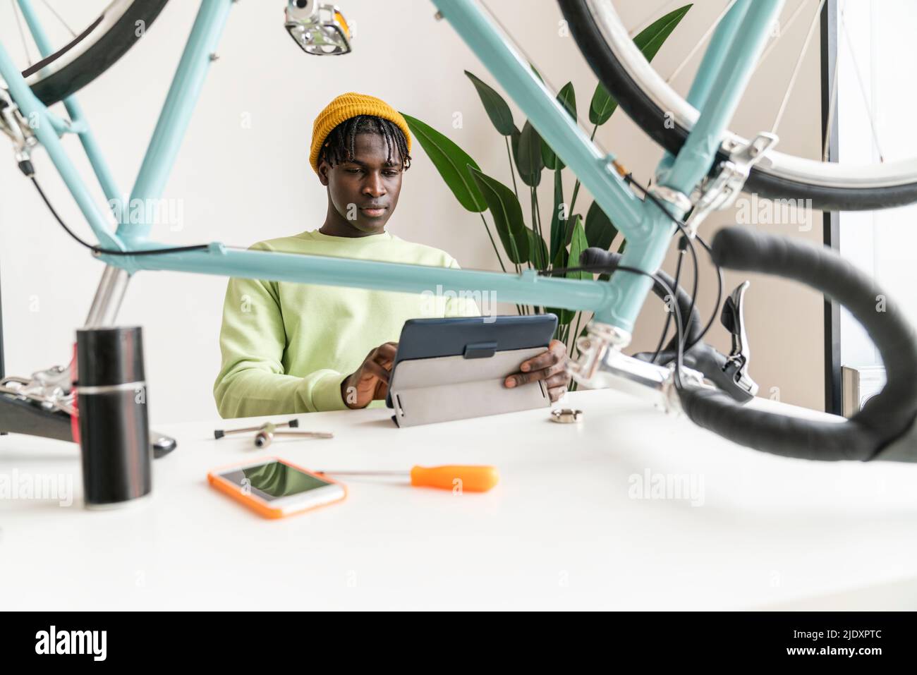 Homme regardant le tutoriel de réparation de vélo sur un PC tablette à la maison Banque D'Images