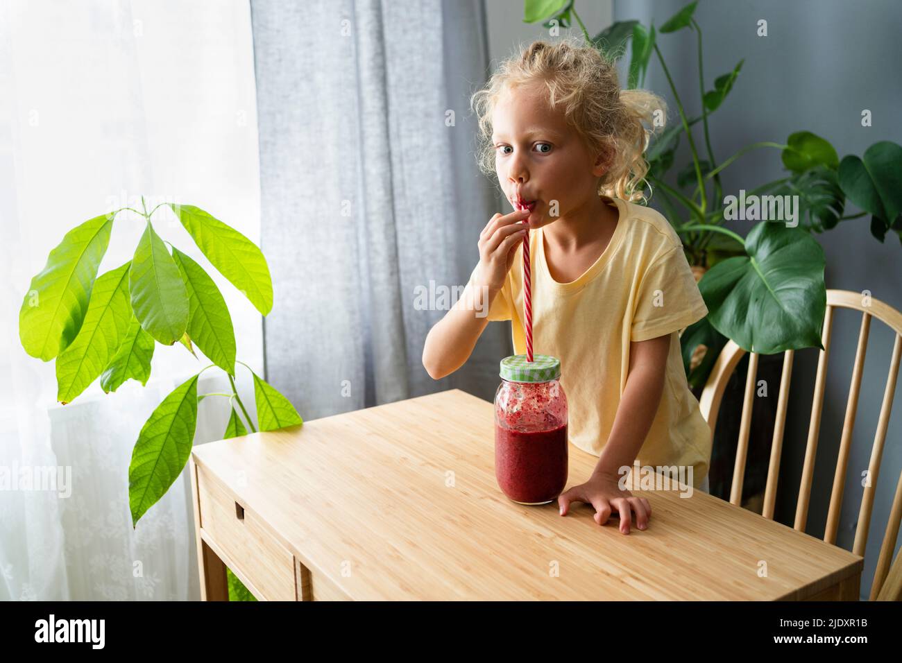 Une fille boit du smoothie dans la paille à la maison Banque D'Images