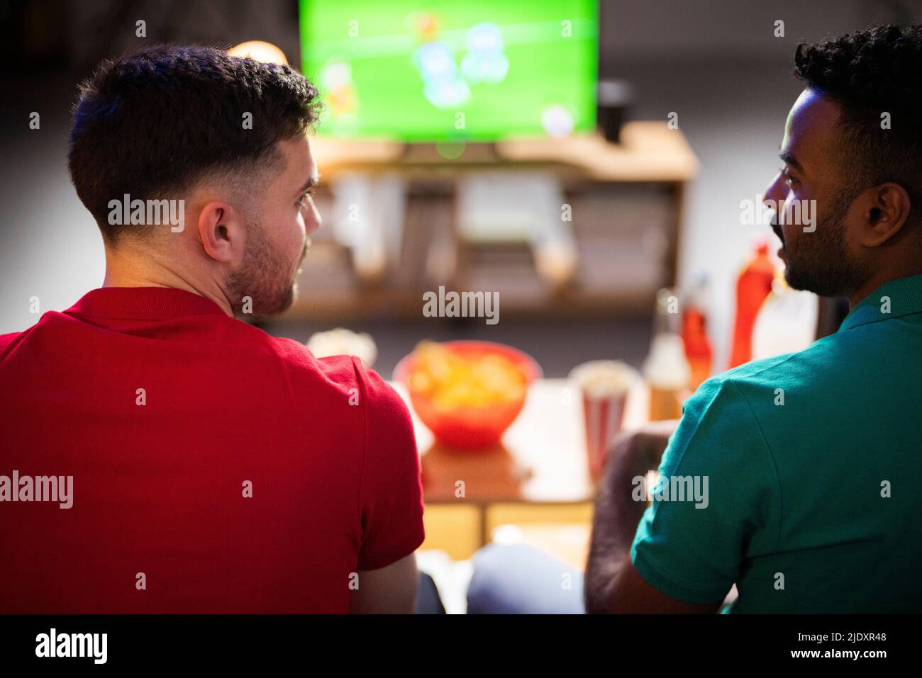 Des amis qui parlent les uns avec les autres en regardant un match de football à la maison Banque D'Images