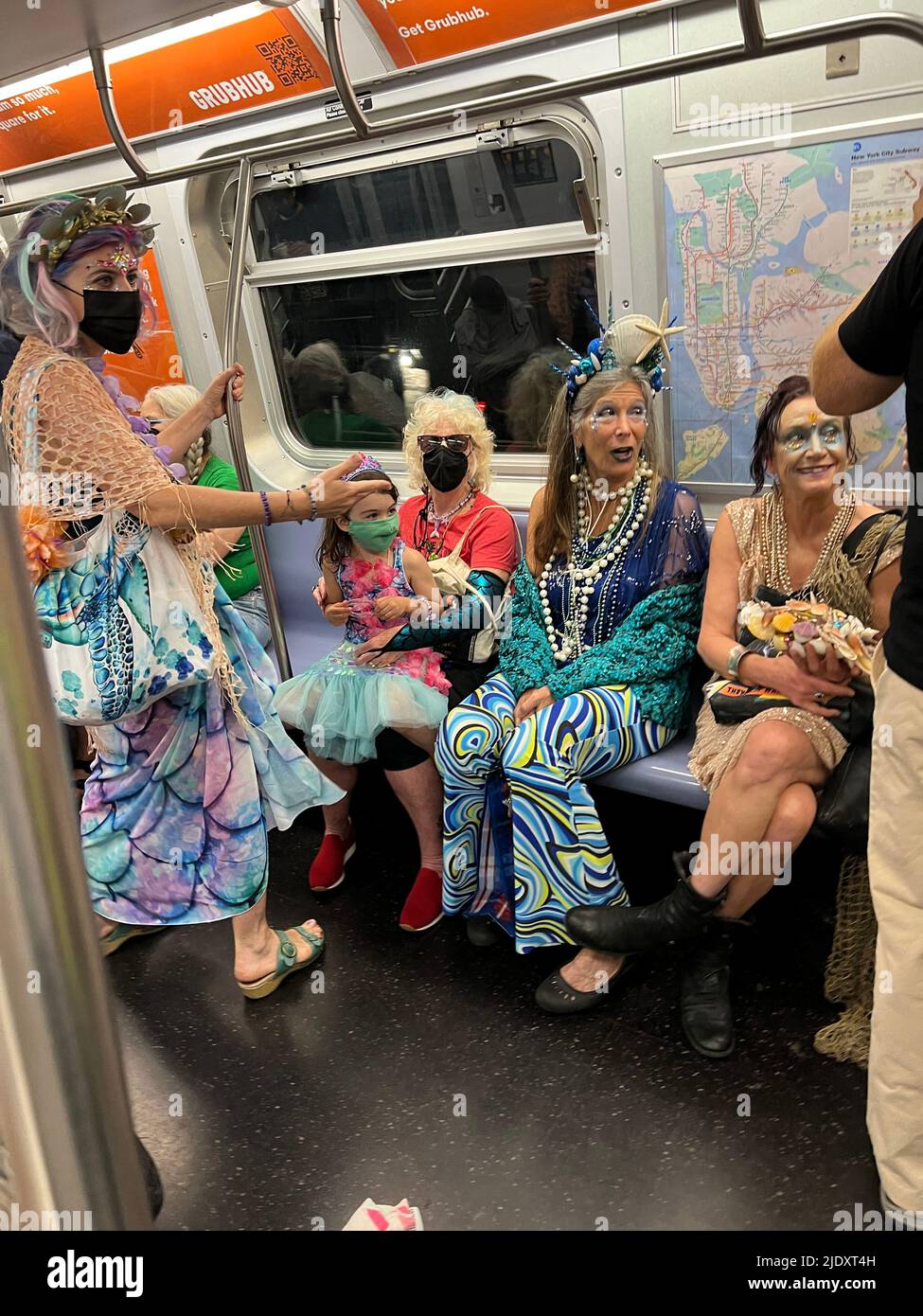 Le train F pour Coney Island est plein de demoiselles colorées et de personnes avec d'autres robes colorées sur leur chemin à la Mermaid Parade annuelle ouvrant la saison d'été à Brooklyn, New York. Banque D'Images