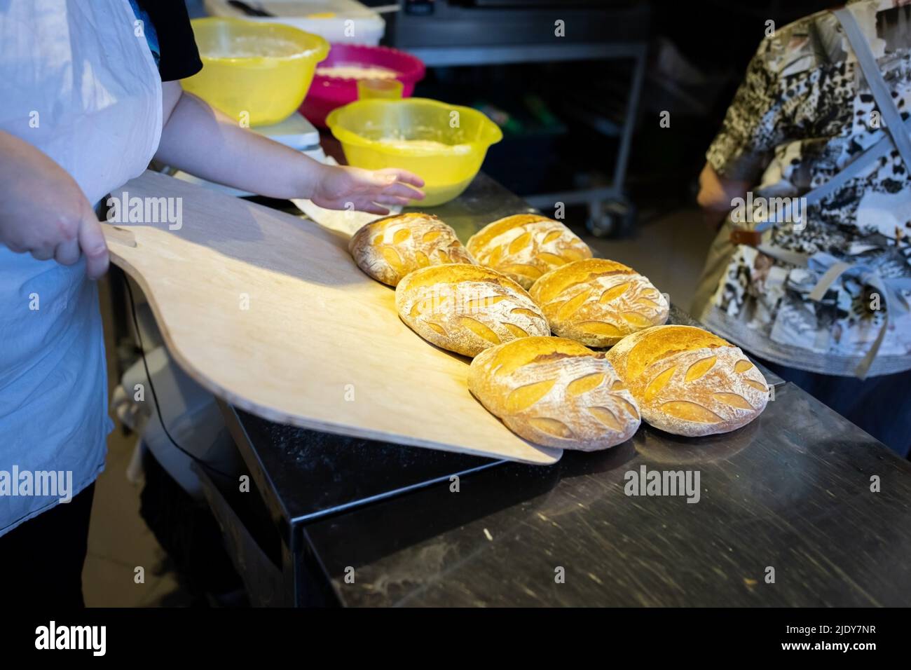 Un boulanger décharge un lot fini de pain de blé artisanal frais du four avec une pelle. Vue avant. Banque D'Images