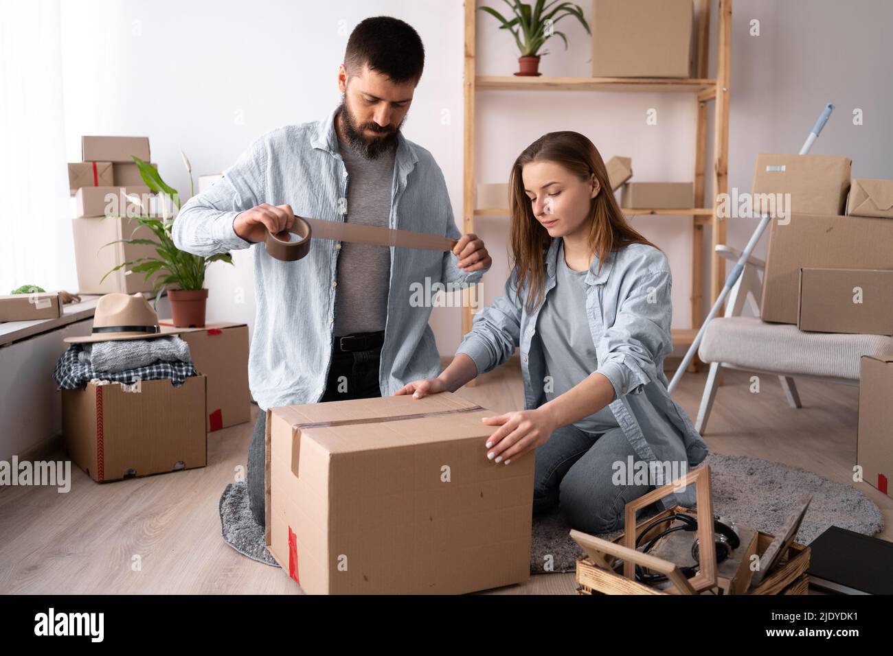Homme et femme emballant le jour de déplacement. Guy scellant une boîte en carton avec du ruban adhésif, déplacement et concept de déplacement. Espace de copie. Banque D'Images