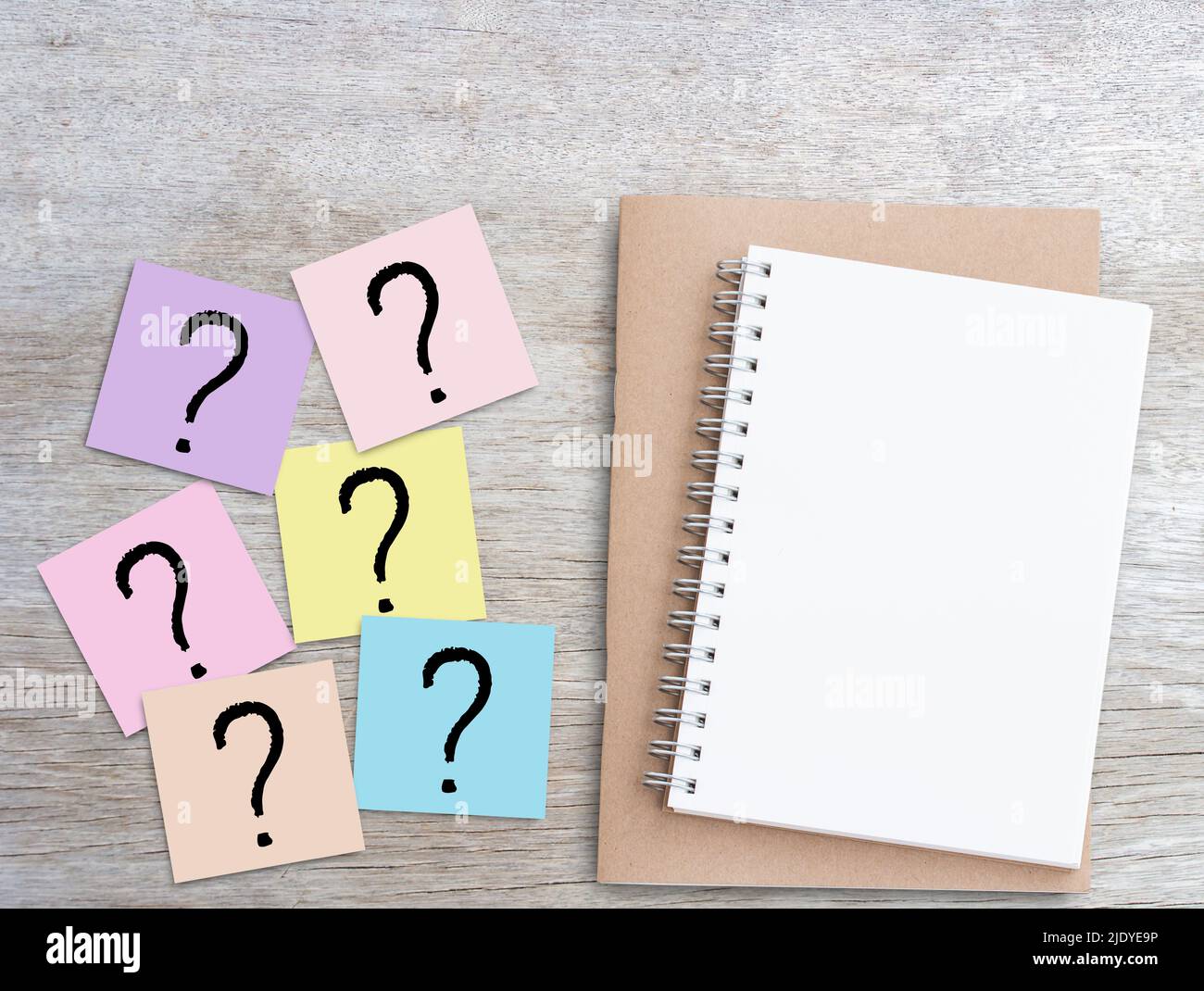 Point d'interrogation sur les notes adhésives roses et bloc-notes vierge sur fond de table en bois. Conception de concept d'entreprise et d'éducation. Banque D'Images