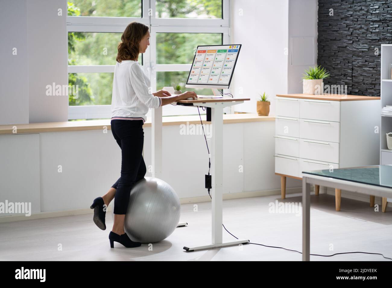 Femme utilisant un bureau à hauteur réglable dans le bureau pour une bonne posture Banque D'Images