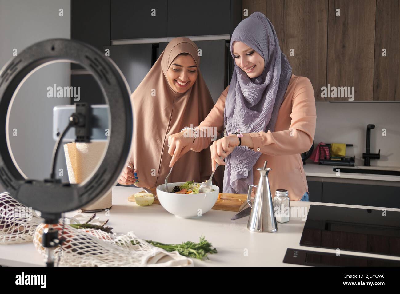 Deux bûcherons musulmans souriant tout en lançant une salade dans la cuisine. Banque D'Images