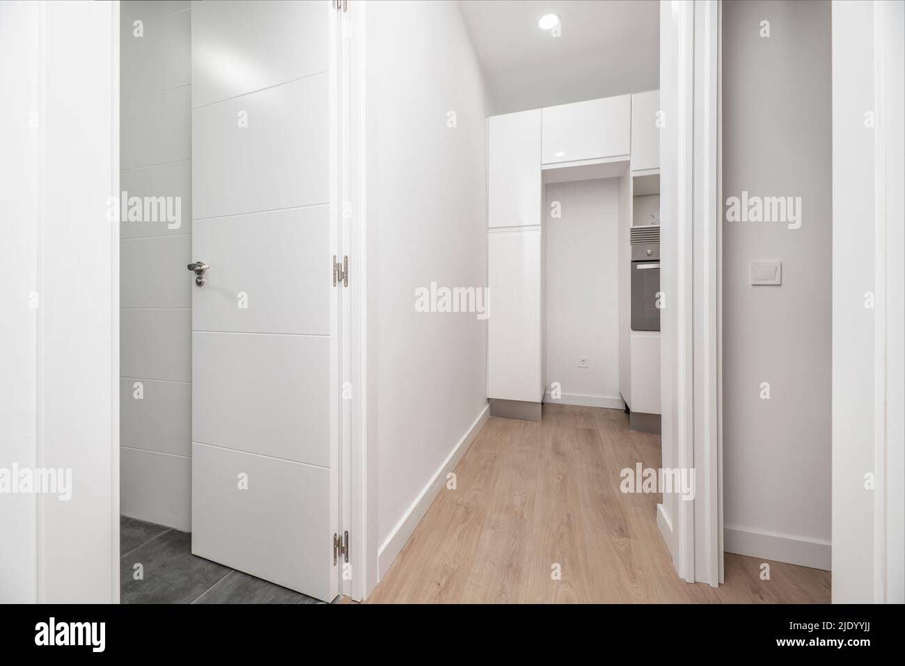 Couloir d'appartement vide avec couloirs en chêne clair, portes d'autres chambres, murs peints en blanc Banque D'Images